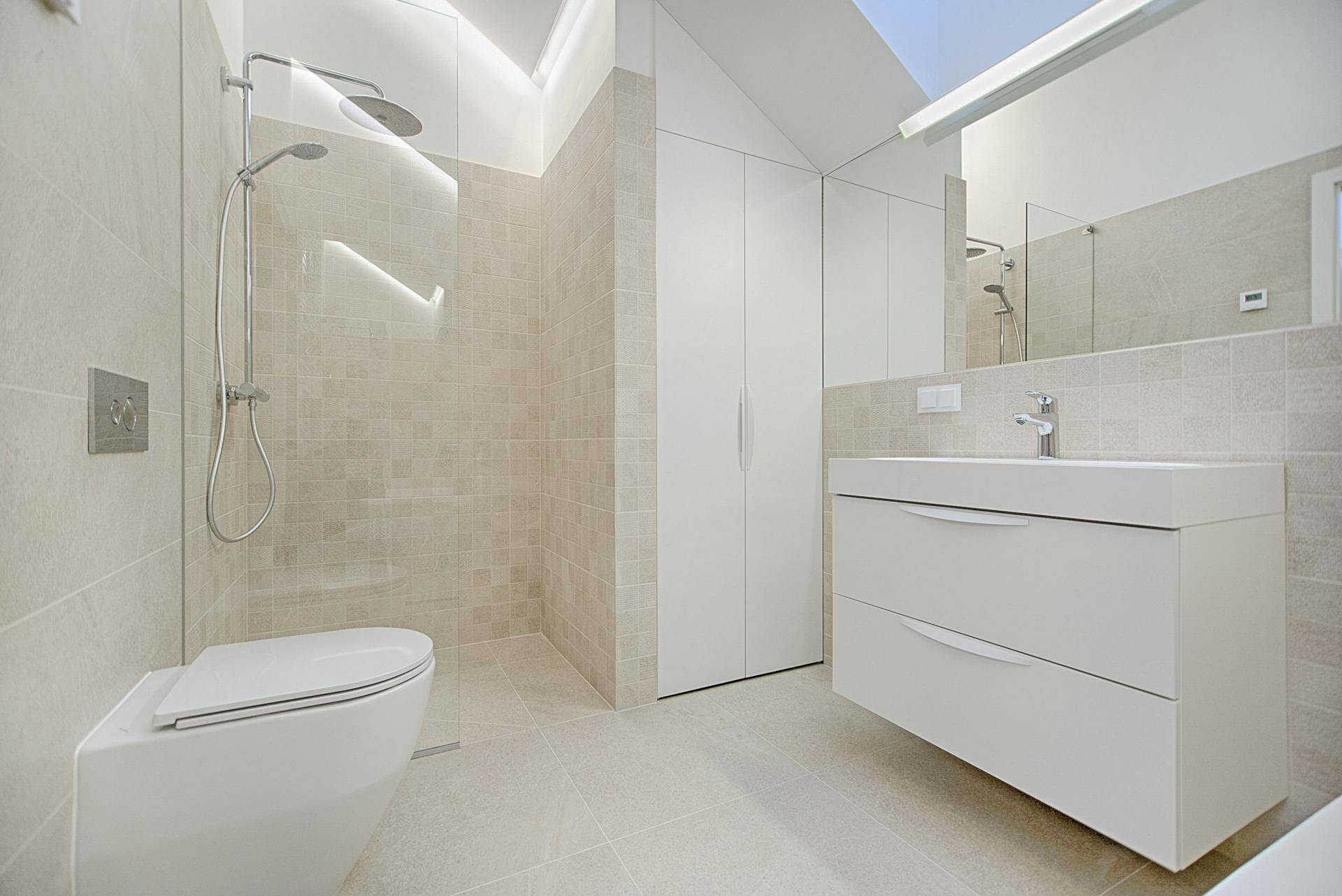 Salle de bain moderne rénovée avec douche à l’italienne, carrelage beige et meuble vasque design.